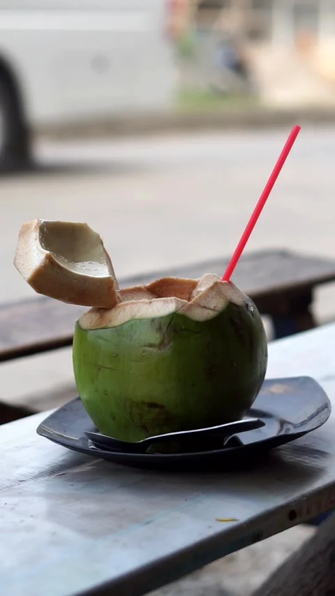 Fresh young coconut ready to drink, served with a red straw. Stock Footage 338394781