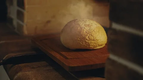 Freshly baked aromatic loaf of bread in a traditional stone oven on fire, Stock Footage 279230357