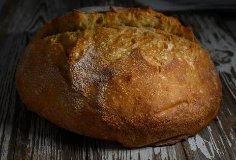 Freshly baked artisan bread resting on rustic wooden table after a warm ove.. Stock Photos