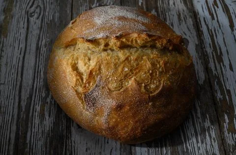 Freshly baked artisan bread on rustic wooden surface showcasing its golden .. Stock Photos