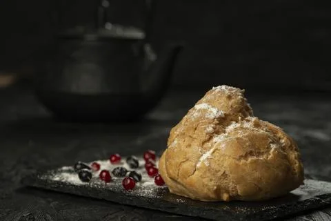 Freshly baked big eclair on a black cutting board Stock Photos