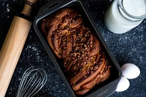 Freshly baked braid bread garnished with walnut chunks with a jug of milk and Stock Photos
