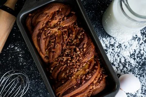 Freshly baked braid bread garnished with walnut chunks with a jug of milk and Stock Photos