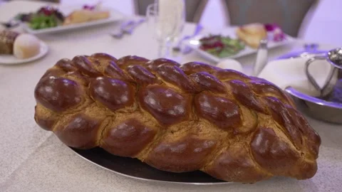 A freshly baked braided challah bread on a platter, central to a festive ta.. Stock Footage 321029412