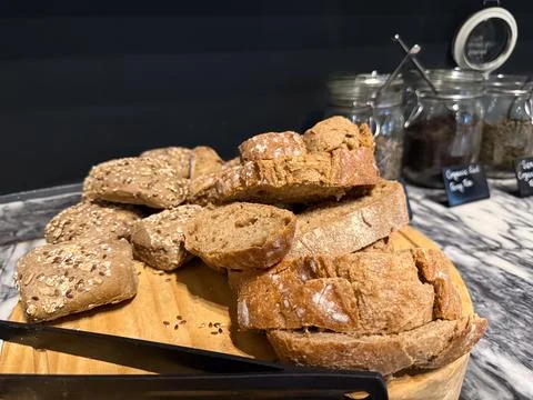 Freshly baked bread and rolls on a wooden board at a buffet, concept of break Stock Photos