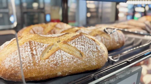 Freshly baked bread being served with tongs in a bakery display case Stock Footage 345677948