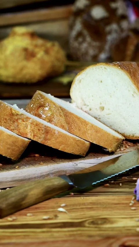Freshly baked bread being sliced, showcasing texture and golden crust in a Stock Footage 320300098