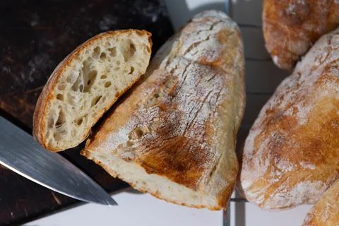 Freshly Baked Bread on a Cooling Rack With a Knife Beside It and a Sliced P.. Stock Photos