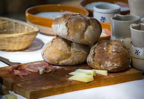 Freshly baked bread on cutting board with cheeses and cold cuts Stock Photos