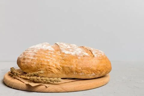 Freshly baked bread on cutting board against white wooden background. persp.. Stock Photos