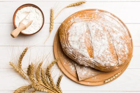 Freshly baked bread on cutting board against white wooden background. top vie Stock Photos