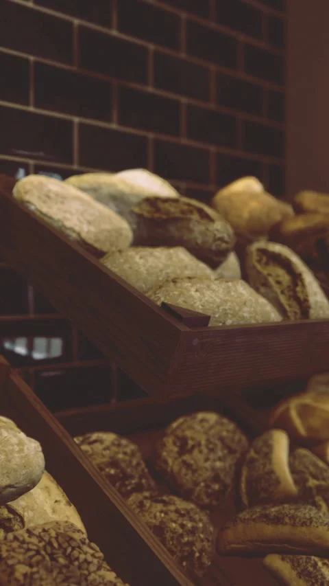Freshly baked bread displayed in a bakery alongside various types and textures Video stock 319569272