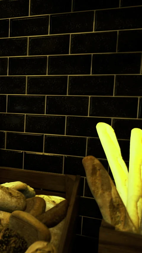 Freshly baked bread displayed in rustic wooden crates on black tiled wall Stock Footage 331690190