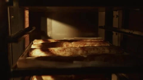 Freshly baked bread loaves resting on metal racks inside an industrial oven, Stock Footage 331755491
