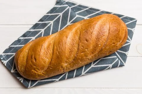 Freshly baked bread with napkin on rustic table top view. Healthy white bre.. 库存照片