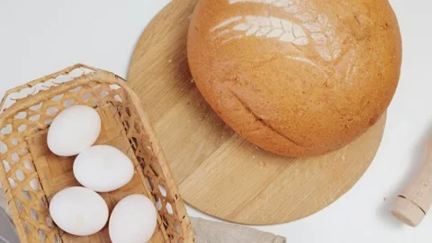 Freshly baked bread with pattern of flour or powder on the table next to eggs Stock Footage 293283051