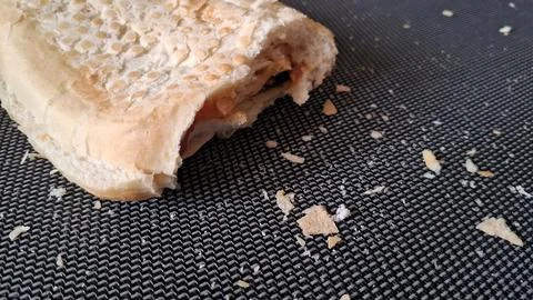 Freshly baked bread roll with visible crumbs on textured surface Stock Photos