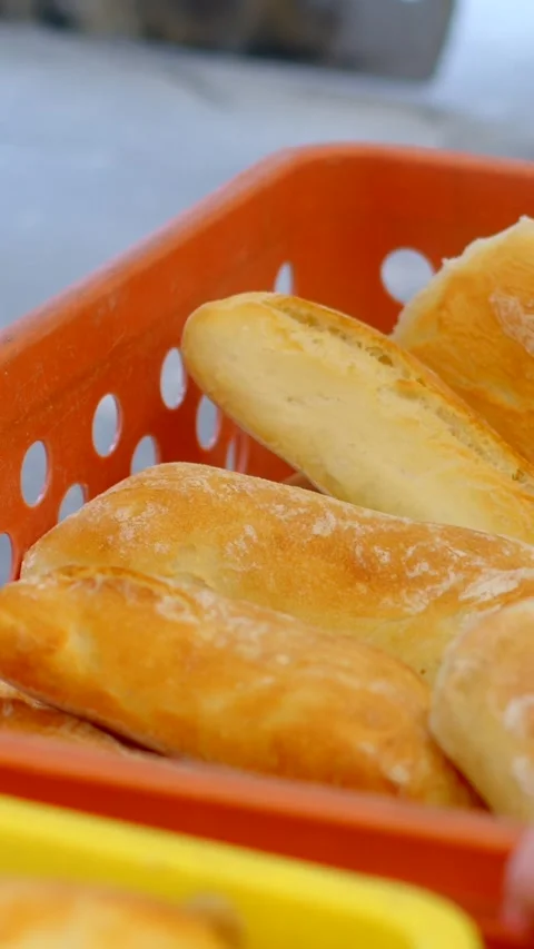 Freshly baked bread rolls being handled in orange crate with hand selection cue Stock Footage 344571753