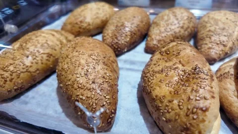 Freshly baked bread rolls covered in sesame seeds displayed on a tray. Stock Footage 332106965