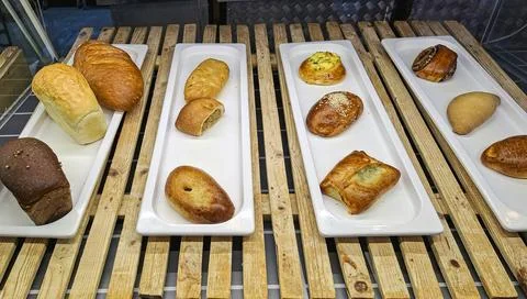 Freshly baked breads and stuffed pastries arranged on trays in a bakery dur.. Stockfoto's