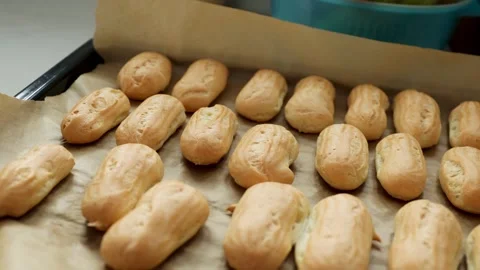 Freshly baked choux pastry shells on tray in sunny kitchen. Stock Footage 337722961