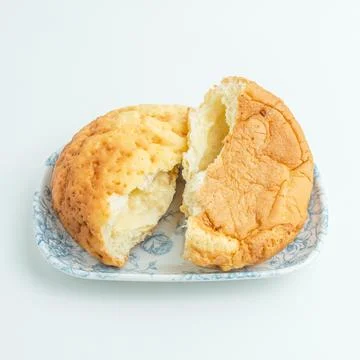 Freshly baked cut bread bun with sweet filling on a white plate isolated on.. Stock Photos