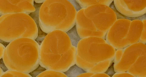 Freshly baked dinner rolls on parchment-lined tray in commercial kitchen, with Stock Footage 344582932