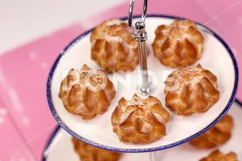 Freshly baked eclairs with icing sugar on a beautiful platform Stock Photos