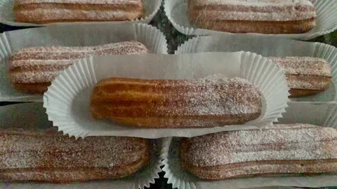 Freshly baked eclairs sprinkled with white powdered sugar. Coffee with eclair Stock Footage 263327822