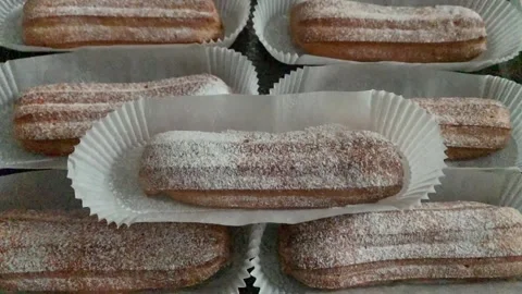 Freshly baked eclairs sprinkled with white powdered sugar. Coffee with eclair Stock Footage 263328064