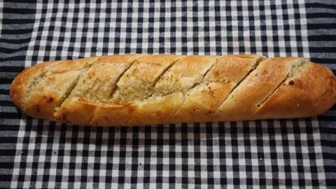 Freshly Baked Garlic Bread Loaf on Checkered Tablecloth Stock Footage 345614279