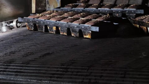 Freshly baked hot bread are leaves of the oven by a conveyor belt at bakery. Stock Footage 245560185