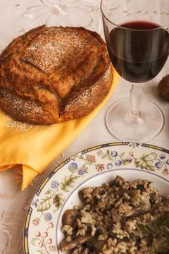 A freshly baked loaf of rustic bread next to a glass of red wine and a plate  Stock Photos