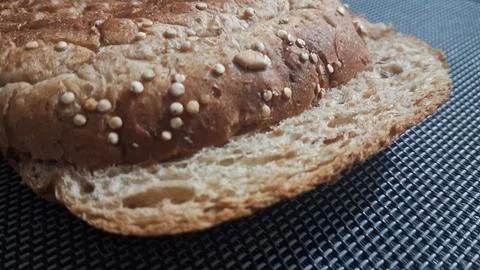 Freshly baked multigrain bread slice with seeds on dark surface Stock Photos