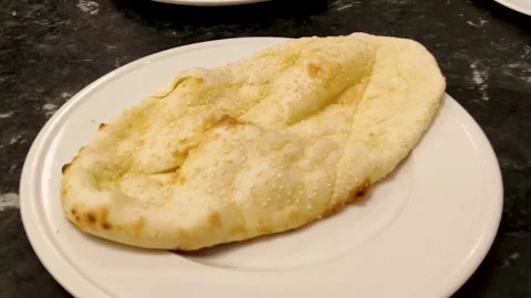 Freshly baked naan flatbread placed on plate for meal serving Stock Footage 320635962