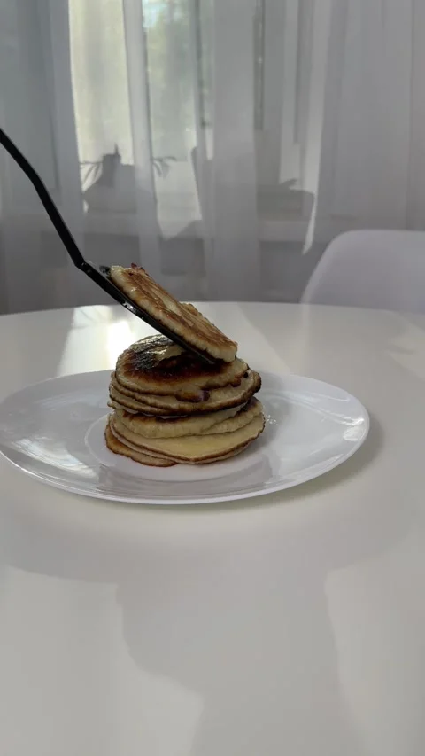 Freshly baked pancakes, adding a new pancake to the stack. cooking pancakes at Stock Footage 245290795