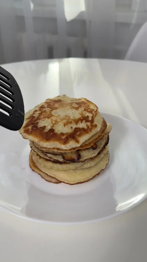 Freshly baked pancakes, adding a new pancake to the stack. cooking pancakes at Stock Footage 245290813