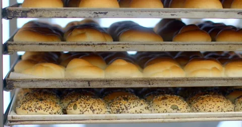 Freshly baked rolls and seeded buns stacked on metal bakery rack with warm roll Stock Footage 344582918