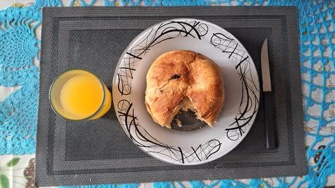 Freshly baked round bread roll served on a patterned white plate Fotos de archivo