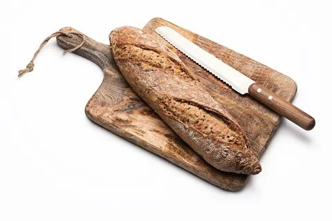 Freshly baked rustic bread baguette with seeds on wooden cutting board isolated 库存照片