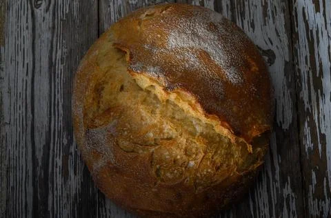 Freshly baked rustic bread with a crispy crust resting on a wooden table Stock Photos