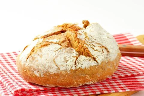 Freshly baked rustic bread on red checkered cloth Stock Photos