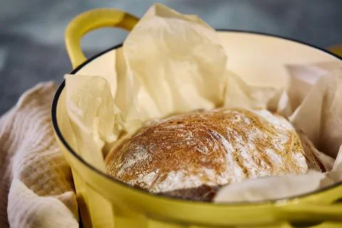 Freshly baked rustic bread in yellow cast iron Dutch oven Description: Stock Photos