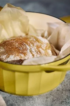 Freshly baked rustic bread in yellow cast iron Dutch oven Description: Stock Photos
