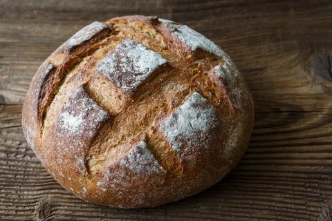 A freshly baked rustic, loaf of bread on an old wooden table Stock Photos