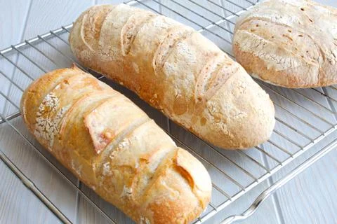 Freshly baked rustic loaves of bread on wooden board Stock Photos