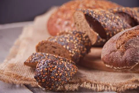 Freshly baked rye bread with cereal and seeds on wooden kitchen table Stock Photos