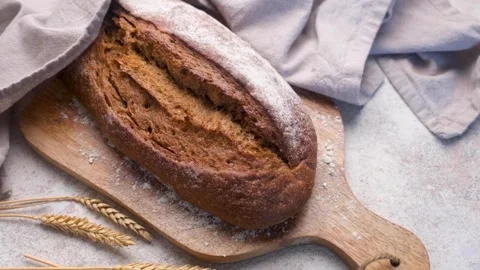 Freshly baked rye bread loaf resting on wooden board Stock Footage 334837932