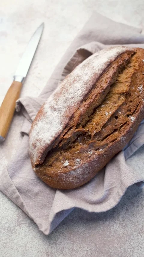 Freshly baked rye bread loaf resting on linen napkin Stock Footage 335632166