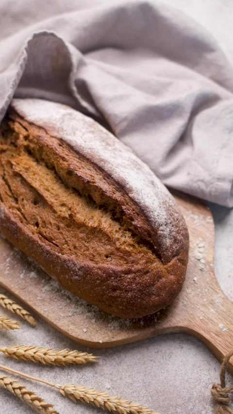 Freshly baked rye bread loaf resting on wooden board Stock Footage 335632192